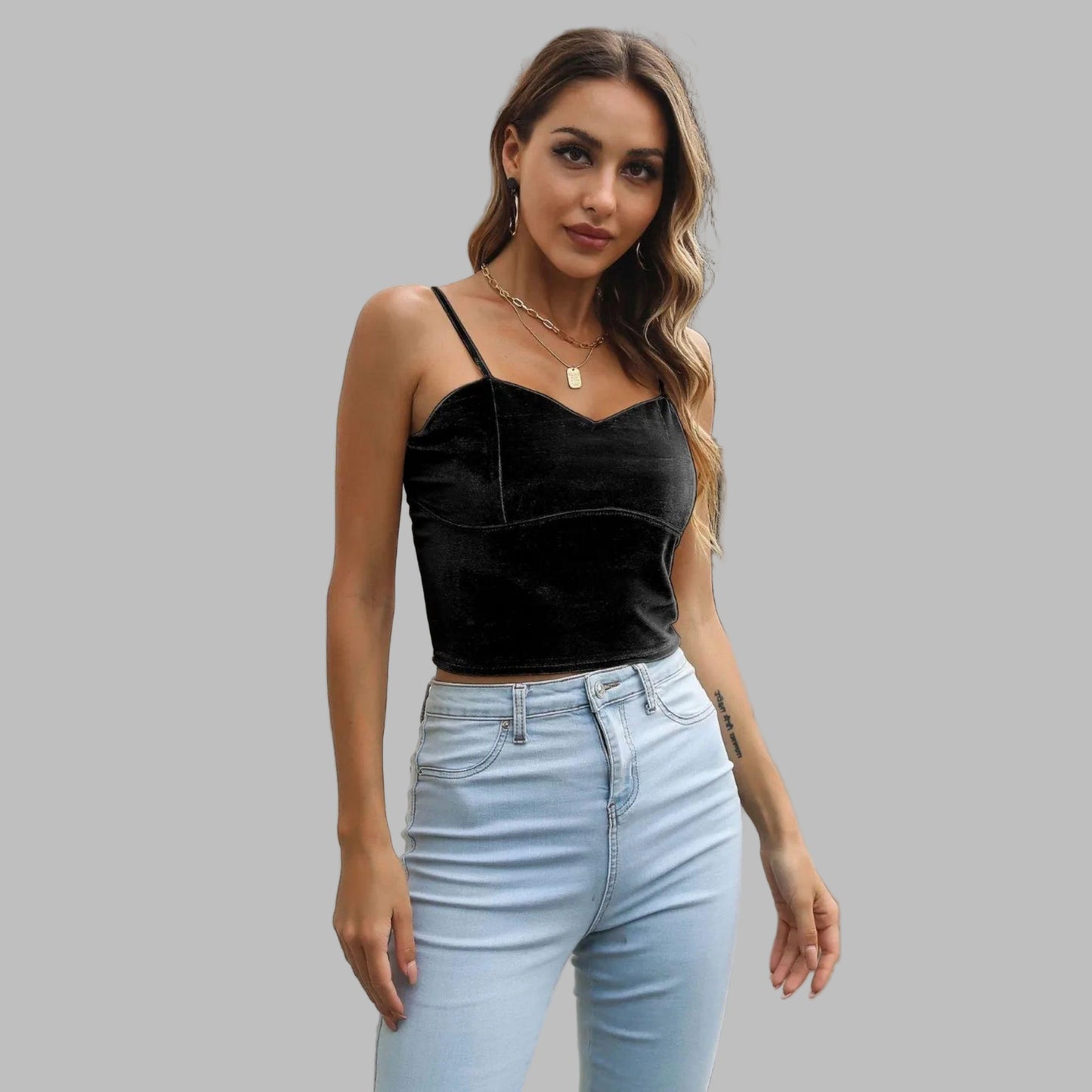 Woman wearing a black top and light blue jeans standing on a street.