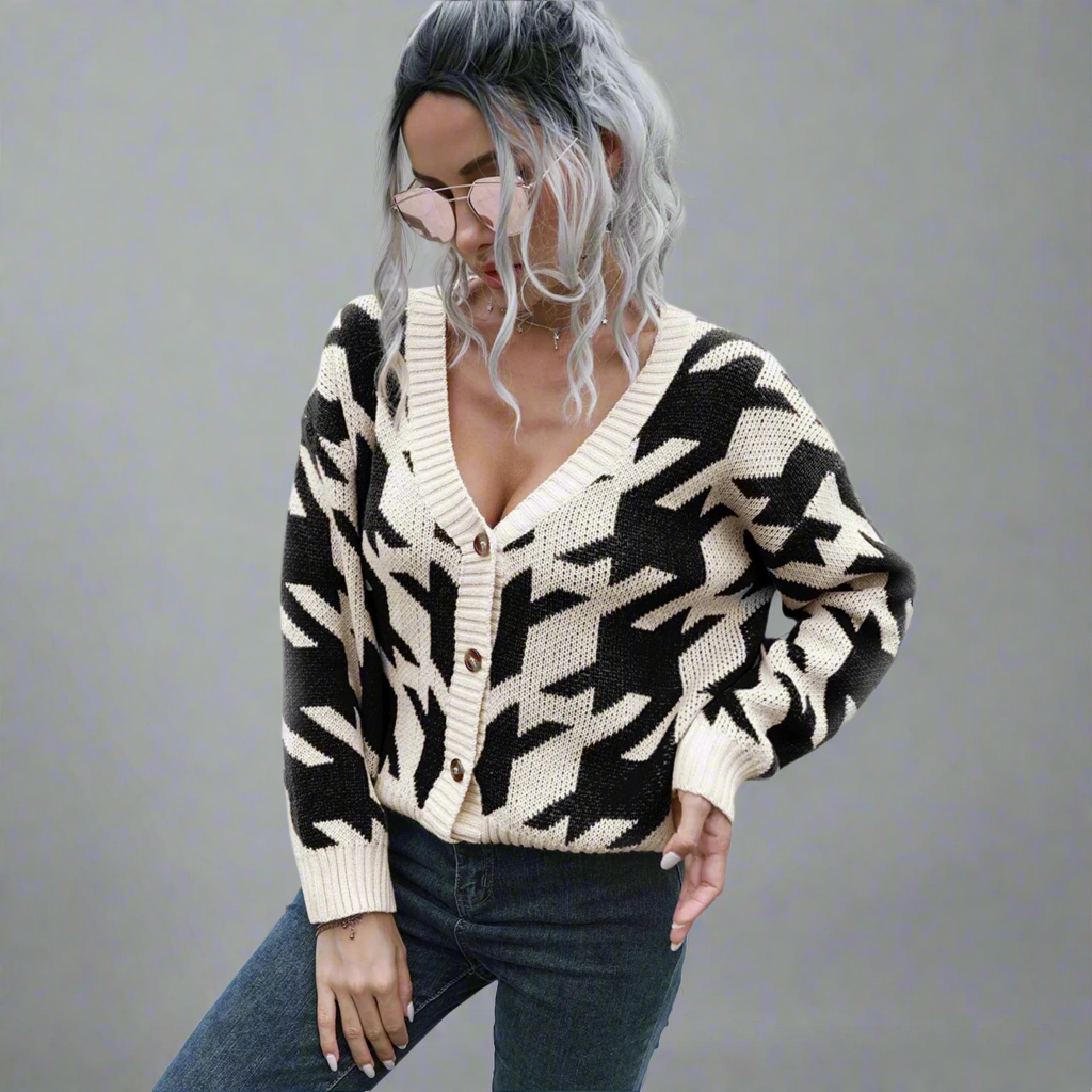 Person wearing a black and white patterned cardigan in an outdoor setting.