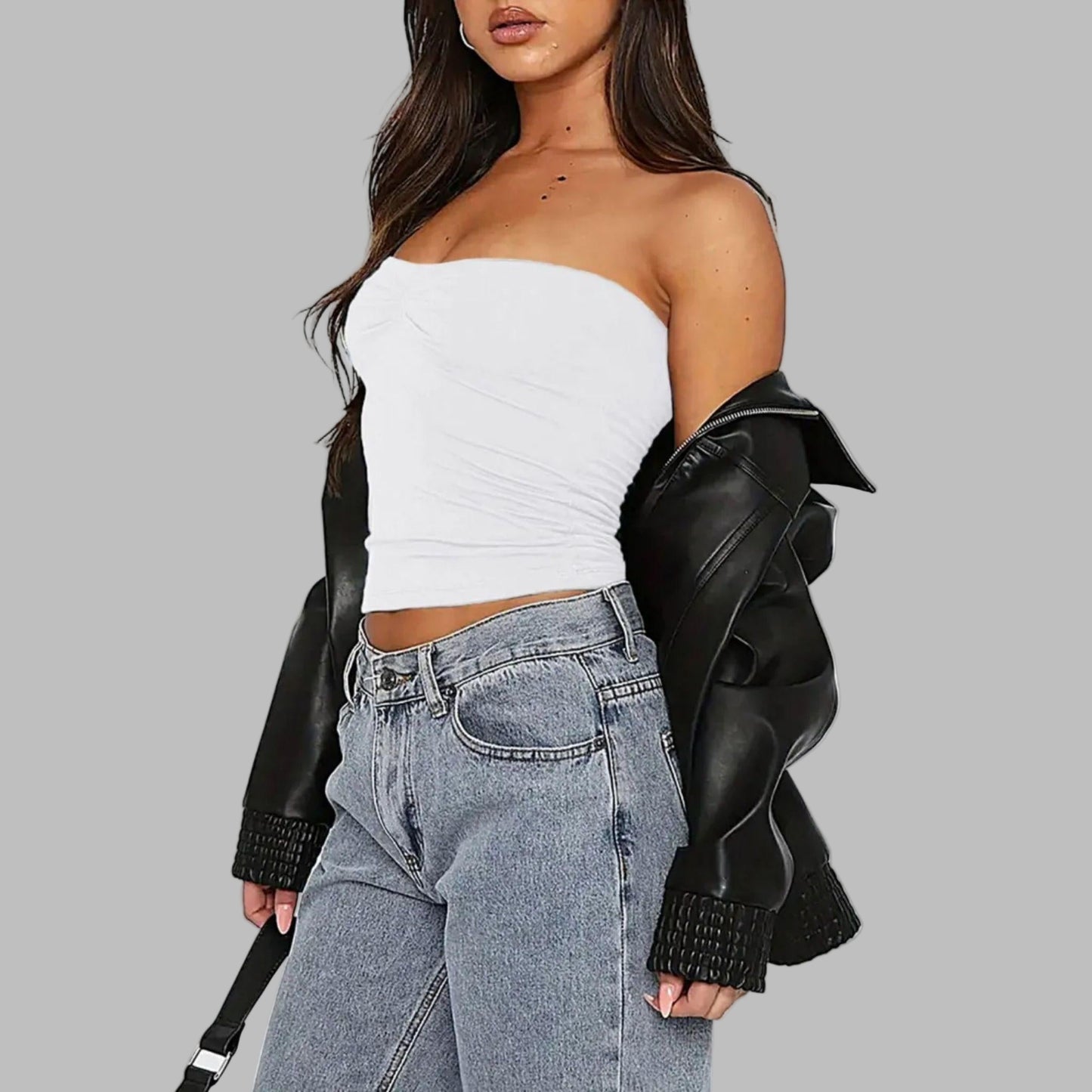 Person wearing a white strapless top, gray jeans, and a black leather jacket on a white background