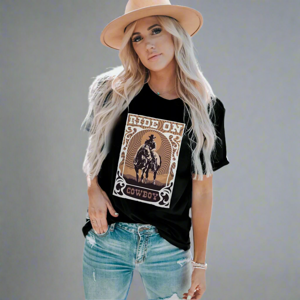 Woman wearing a black t-shirt with a graphic design and a beige hat on a gray background