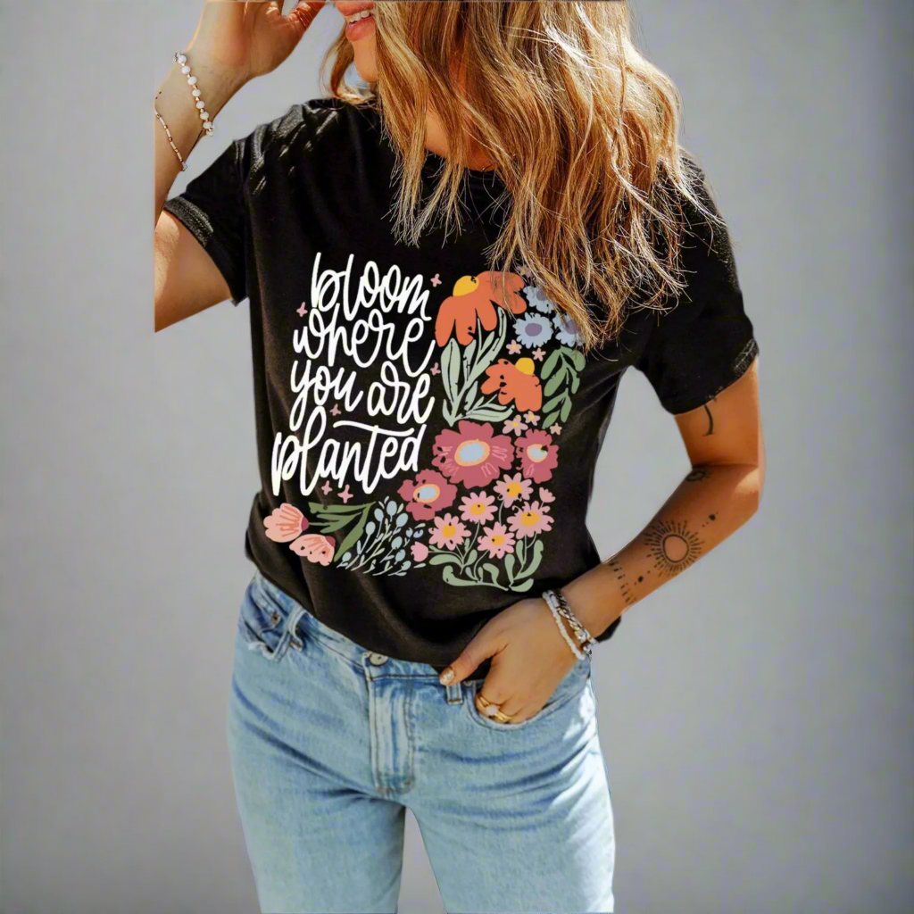 Person wearing a black t-shirt with floral design and text on a gray background