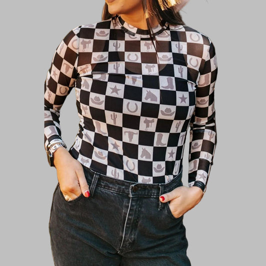 Person wearing a black and white checkered shirt with patterned design, standing outdoors.