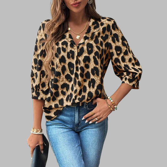 Woman wearing a leopard print top and blue jeans indoors.