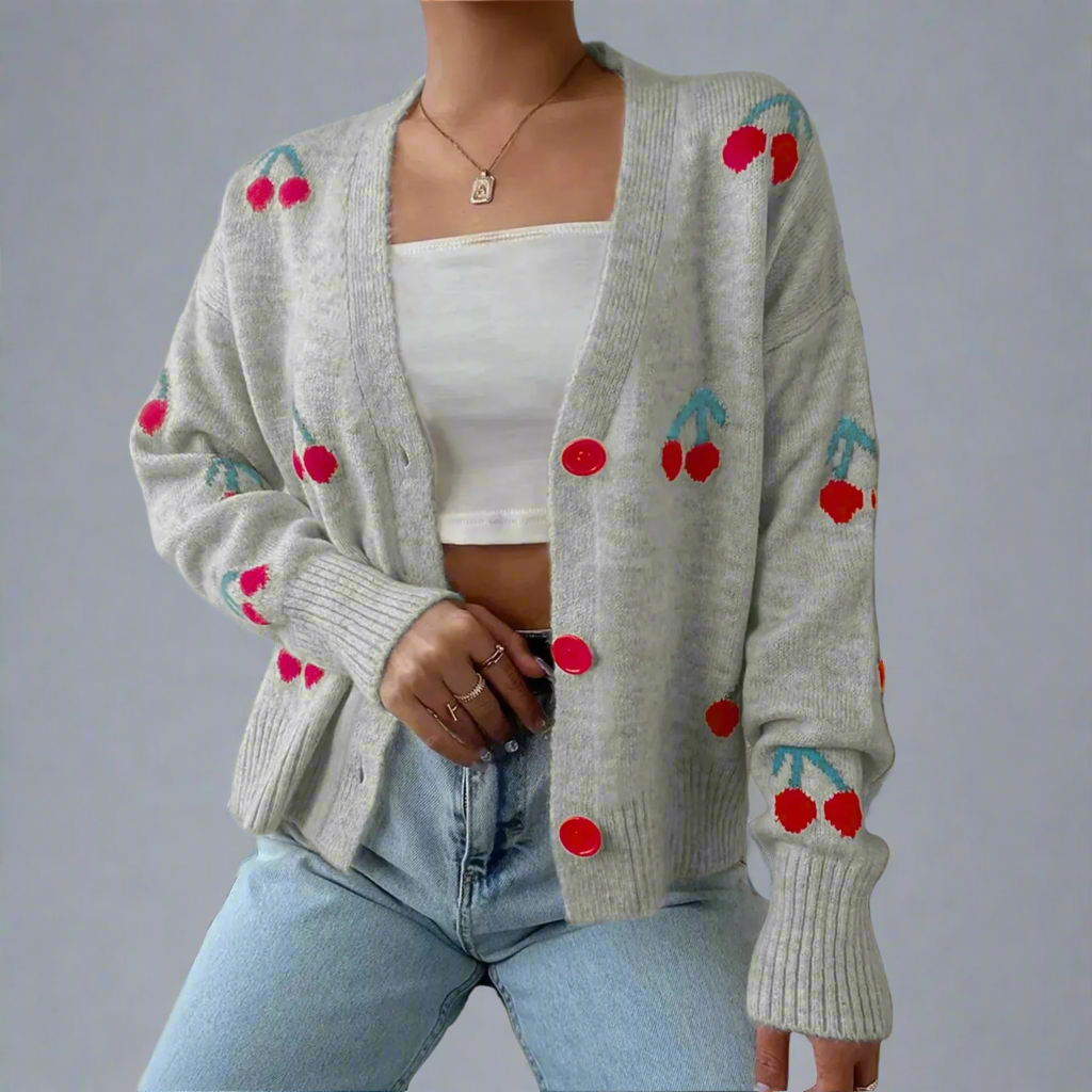 Gray cardigan with cherry designs worn by a person against a neutral background