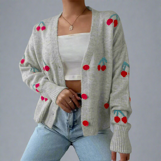 Gray cardigan with cherry designs worn by a person against a neutral background