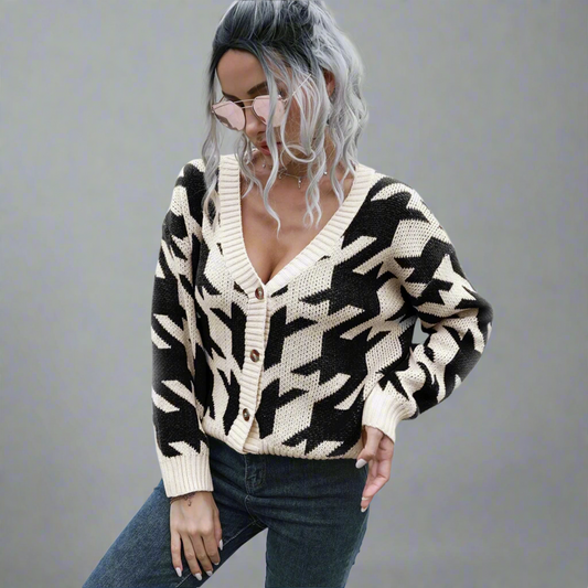 Person wearing a black and white patterned cardigan in an outdoor setting.