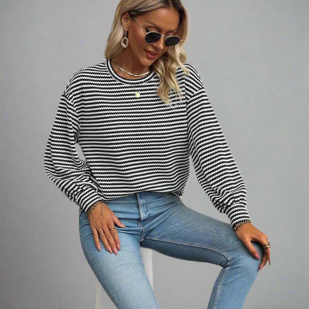 Woman wearing a black and white striped sweater and blue jeans on a white background