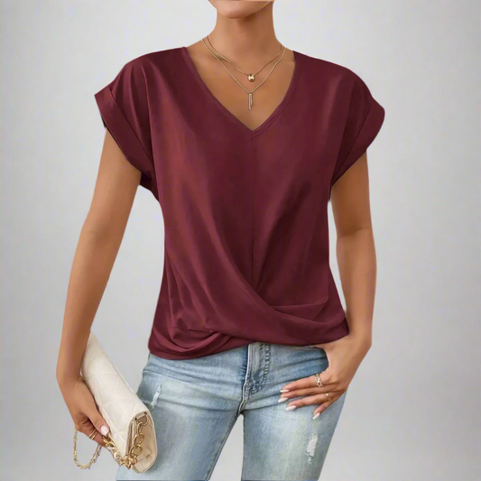 Woman wearing a burgundy top and blue jeans against a gray background