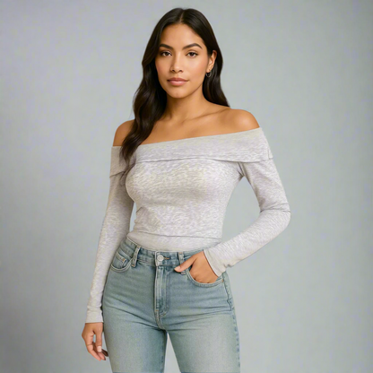 Woman wearing a gray off-shoulder top and light blue jeans on a gray background