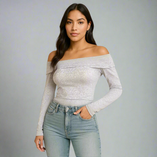 Woman wearing a gray off-shoulder top and light blue jeans on a gray background