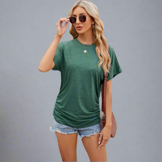 Woman wearing a green t-shirt and denim shorts against a gray background